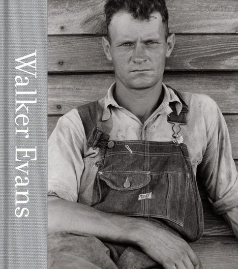 Text "Walker Evans". Ein Mann in Latzhose lehnt an einer Holzwand, blickt ernst nach vorn. Vintage Fotografie.