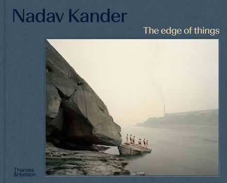 "Nadav Kander", "The edge of things". Menschen stehen auf einem Felsen am Flussufer, im Hintergrund ist Rauch zu sehen.