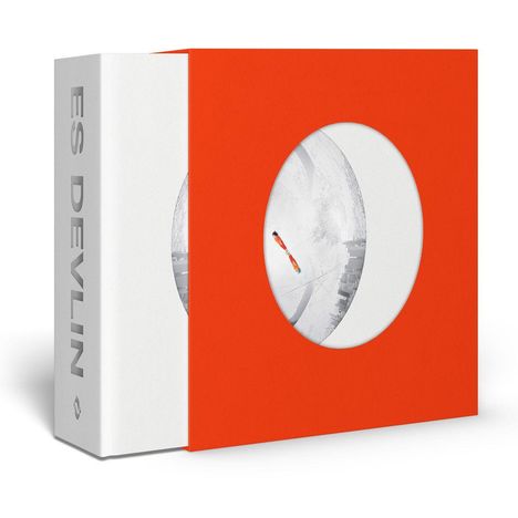 Der Text "ES DEVLIN" ist auf einem weißen Buchrücken zu sehen. Ein oranges Cover mit rundem Ausschnitt zeigt abstrakte Formen.
