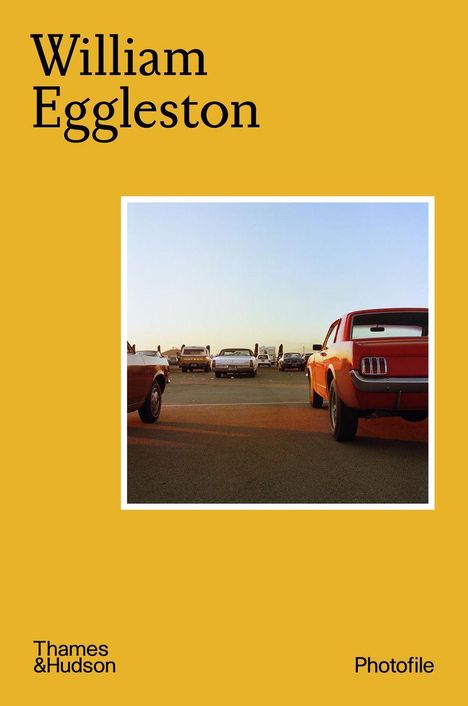 „William Eggleston“. Foto zeigt Autos auf einem Parkplatz bei Sonnenuntergang. Gelber Hintergrund, Text links.