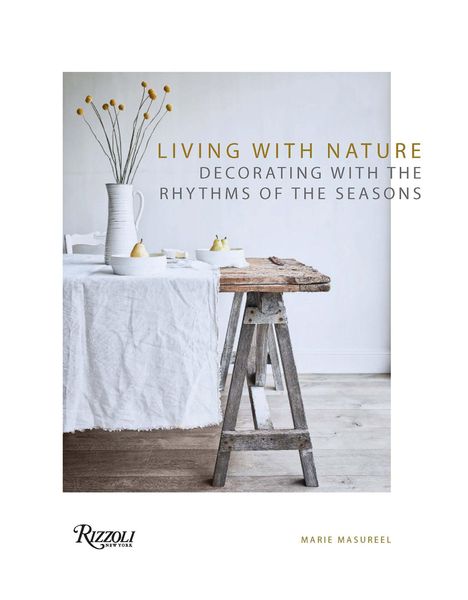 Titel: LIVING WITH NATURE. Ein rustikaler Tisch mit Vase, Tassen und Birnen in einem hellen Raum.