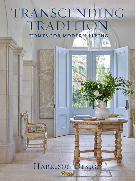 "TRANSCENDING TRADITION. HOMES FOR MODERN LIVING. HARRISON DESIGN." Ein elegantes Interieur mit blauen Türen und hellem Tisch.