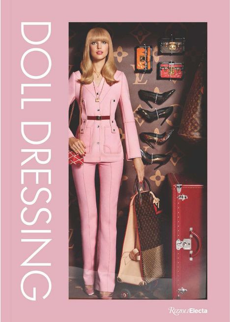 „DOLL DRESSING“ in großen Buchstaben links. Frau in rosa Anzug, Luxusartikel im Hintergrund.