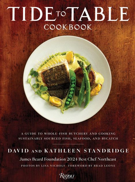 „Tide to Table Cookbook“: Ein Teller mit Fisch, Erbsen, Spargel und Muscheln auf einer Holztisch-Optik.