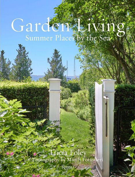 „Garden Living: Summer Places by the Sea“. Blick durch ein Gartentor auf Rasen, Büsche und Bäume mit Meer im Hintergrund.