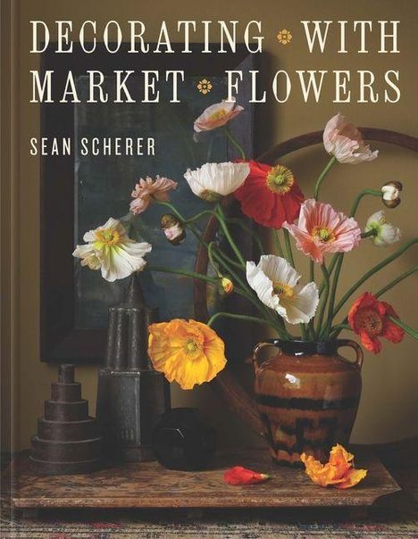 „Decorating with Market Flowers, Sean Scherer“. Ein Bouquet bunter Blumen in einer Vase neben geometrischen Objekten.