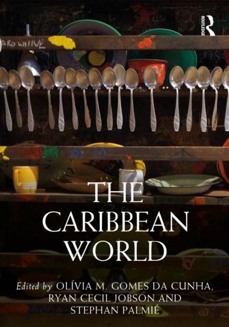 "The Caribbean World" in Weiß auf dunklem Hintergrund. Löffel hängen über buntem Geschirr.