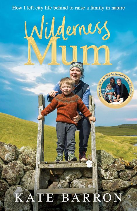 "Wilderness Mum" von Kate Barron. Auf einer Wiese stehen eine lächelnde Frau und ein Kind hinter einer Steinmauer.