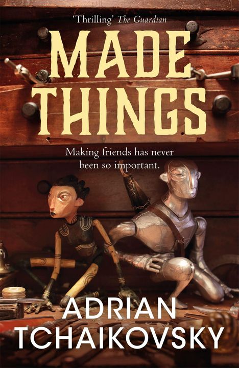 Text: „MADE THINGS“, „Making friends has never been so important.“, „'Thrilling' Guardian“, „Adrian Tchaikovsky“. Zwei Puppen: eine aus Holz, eine aus Metall, in einem Schrank.