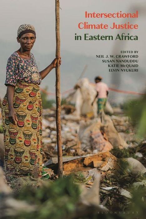 "Intersectional Climate Justice in Eastern Africa" steht auf einem Müllplatz. Eine Frau lehnt an einem Stock, weitere Personen im Hintergrund.