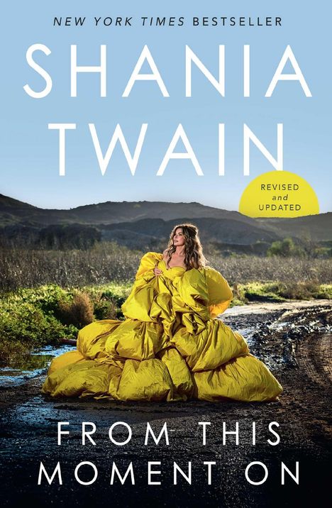 NEW YORK TIMES BESTSELLER, SHANIA TWAIN, FROM THIS MOMENT ON. Frau im gelben Kleid vor Hügeln und blauem Himmel.
