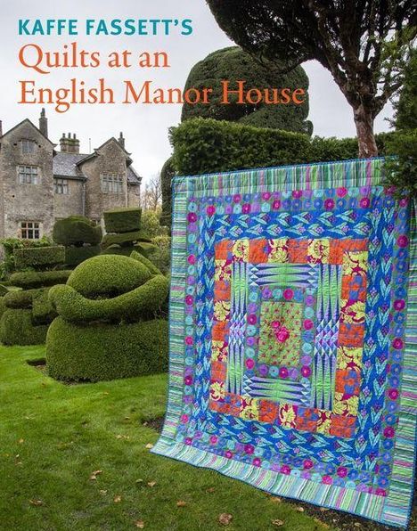 Text: "KAFFE FASSETT'S Quilts at an English Manor House." Ein farbenfroher Quilt vor einem Herrenhaus mit kunstvollen Hecken.