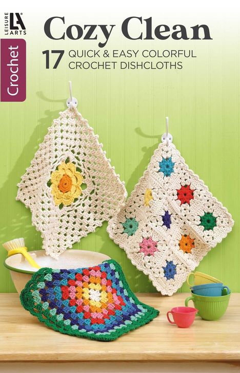„Cozy Clean“, „17 Quick & Easy Colorful Crochet Dishcloths“. Drei bunte, gehäkelte Spültücher an Haken.