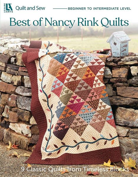 „Best of Nancy Rink Quilts“, bunte Decke auf Steinmauer, herbstliche Blätter.