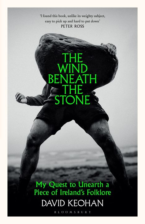 "THE WIND BENEATH THE STONE. My Quest to Unearth a Piece of Ireland's Folklore. DAVID KEOHAN. Schwarz-weißes Foto eines Mannes, der einen großen Stein über dem Kopf hält."
