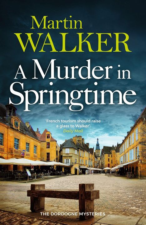 "Martin WALKER, A Murder in Springtime, Daily Mail." Historischer Platz mit gelben Gebäuden und Cafés unter dramatischem Himmel.