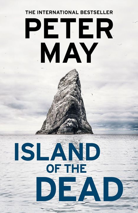 "The International Bestseller - Peter May. Island of the Dead. Einsamer Felsen im ruhigen Meer, grauer Himmel."
