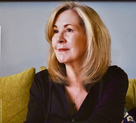 TEXT: "PHOTO BY ALEYSA DUNN".  
Eine Frau mit mittellangem Haar sitzt entspannt auf einem gelben Sofa.