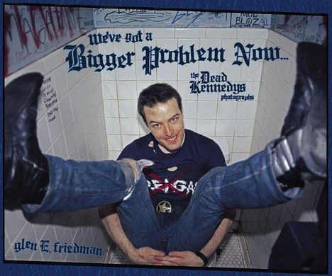 Texte: "We've Got a Bigger Problem Now...", "the Dead Kennedys", "photograph" und "glen E. friedman". Person sitzt lächelnd am Boden.
