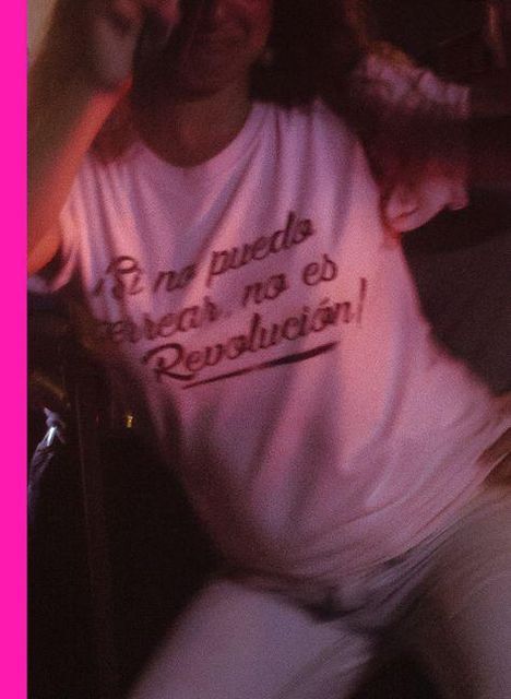 Text: "Si no puedo bailar, no es Revolución!" Auf einem weißen T-Shirt, getragen von einer Person in Bewegung.