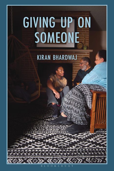 Text: "GIVING UP ON SOMEONE" und "KIRAN BHARDWAJ". Eine Gruppe von Menschen sitzt lächelnd im Wohnzimmer.