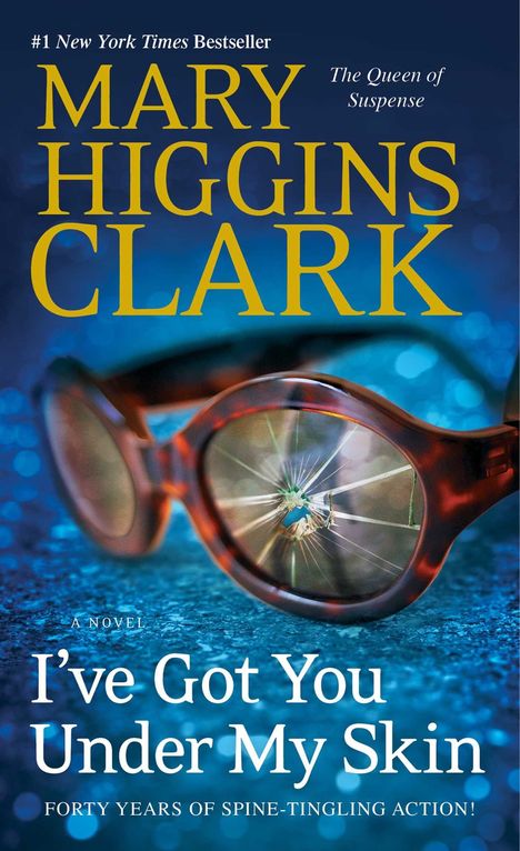 Titel: I’ve Got You Under My Skin. Autorin: Mary Higgins Clark. Brille mit gesprungenem Glas auf blauem Hintergrund.