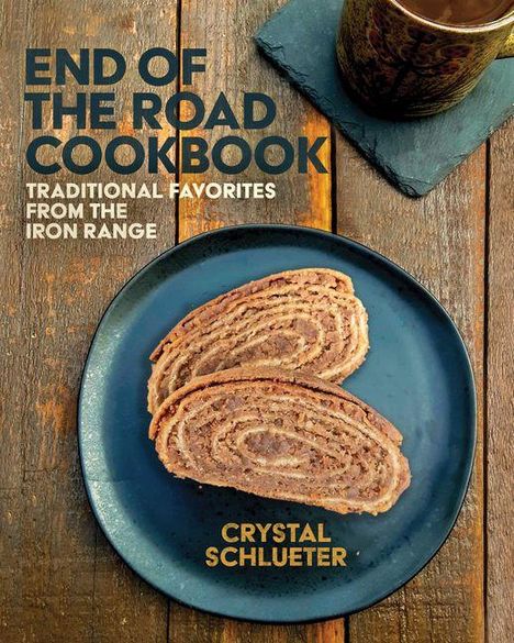 "End of the Road Cookbook" in blauem Text. Darunter zwei Brotscheiben auf einem blauen Teller, Holztischhintergrund.
