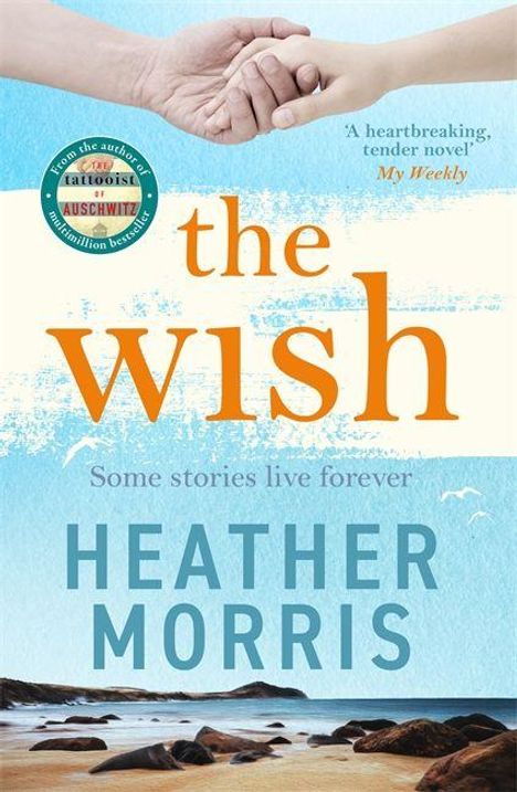 Text: "the wish," "Some stories live forever," "HEATHER MORRIS." Zwei Hände halten sich, darunter Strand und Meer.