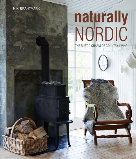"Naturally Nordic" steht in großer Schrift. Ein rustikaler Holzofen vor einer Steinwand, daneben ein Korb mit Holz und ein Stuhl mit Fell.