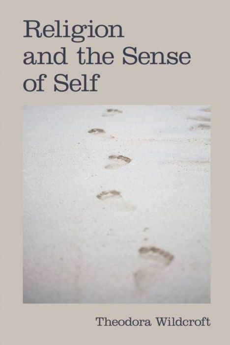 Text: "Religion and the Sense of Self" und "Theodora Wildcroft". Fußspuren führen im Sand in die Ferne.