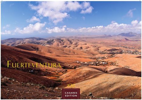 "Fuerteventura" in gelber Schrift, weite karge Landschaft mit sanften Hügeln unter einem blauen Himmel mit Wolken.