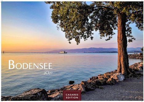 "BODENSEE 2027" und "CASARES EDITION". Ein ruhiger See im Sonnenuntergang, ein Baum, Steine und ein Schiff am Horizont.