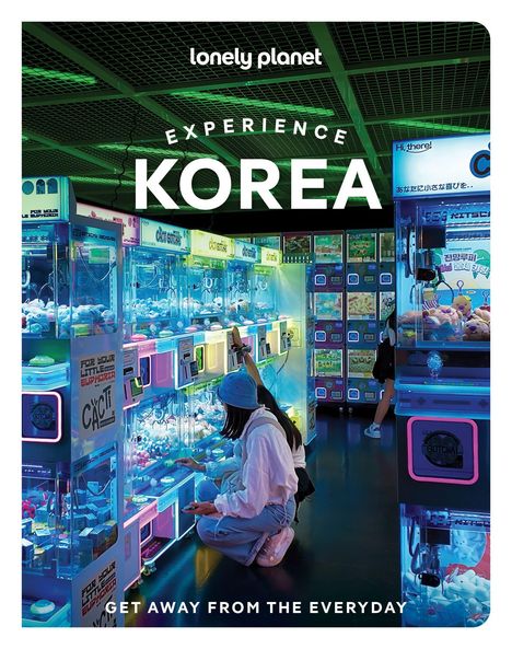 „EXPERIENCE KOREA“, leuchtende Automaten in einem neonbeleuchteten Raum, Menschen bedienen sie.