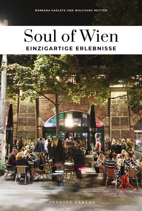 "Soul of Wien: Einzigartige Erlebnisse. Draußen sitzt eine Gruppe von Menschen vor einem beleuchteten Lokal bei Nacht."