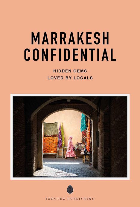 "MARRAKESH CONFIDENTIAL. HIDDEN GEMS LOVED BY LOCALS. Foto eines Tunnels mit einem Marktstand voller bunter Stoffe."
