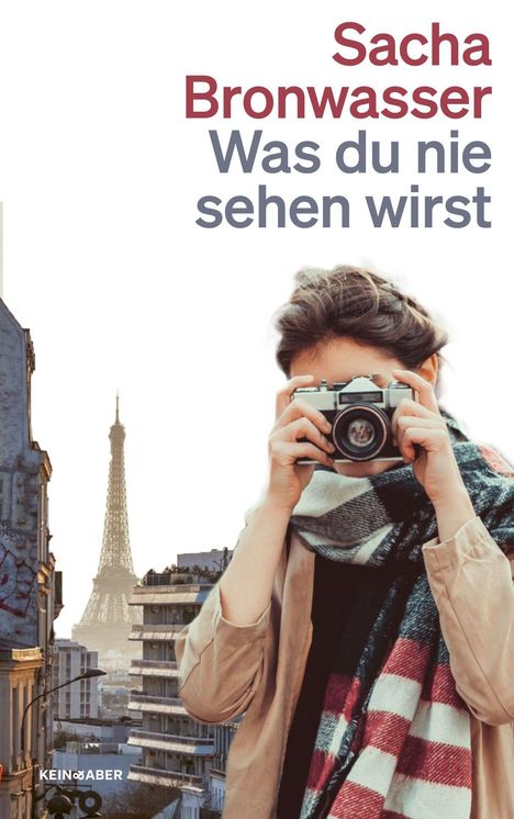 Text: "Sacha Bronwasser Was du nie sehen wirst". Eine Person mit Kamera, im Hintergrund der Eiffelturm.
