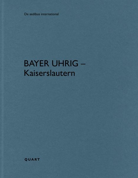 „BAYER UHRIG – Kaiserslautern“ steht groß. Oben „De aedibus international“. Unten „QUART“. Hintergrund einfarbig blau.