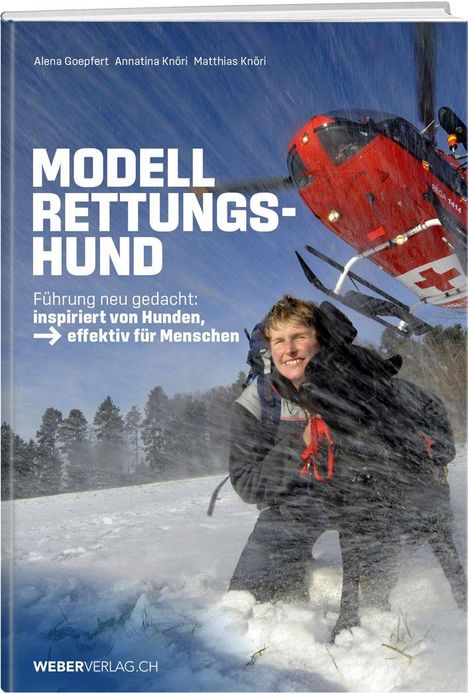 Titel: "Modell Rettungshund". Hubschrauber über Mensch mit Hund im verschneiten Gelände.