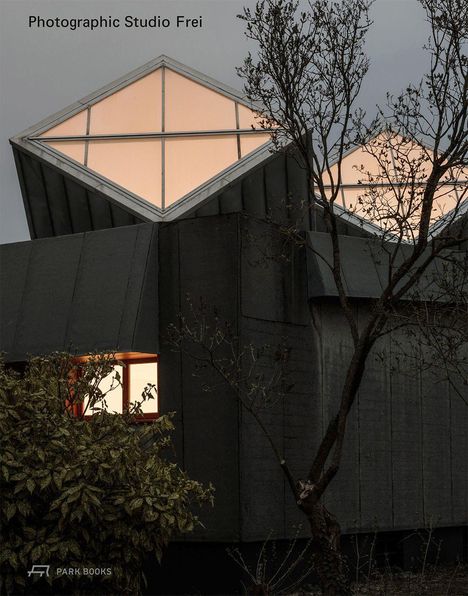 "Photographic Studio Frei"; modernes Gebäude mit markanten, leuchtenden, geometrischen Dachfenstern, umgeben von Bäumen.