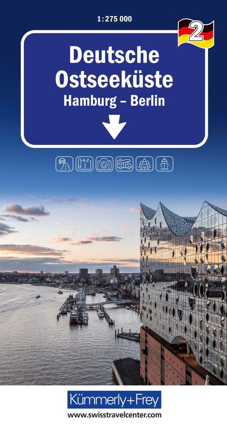 "Deutsche Ostseeküste Hamburg-Berlin" steht groß auf einem blauen Schild über einer Stadtansicht bei Sonnenuntergang.
