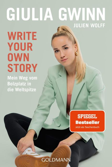 Texte: Giulia Gwinn, Julien Wolff, Write Your Own Story, Mein Weg vom Bolzplatz in die Weltspitze, Spiegel Bestseller. Eine junge Frau in einem mintgrünen Blazer sitzt mit ausgestrecktem Bein und Sneakers.