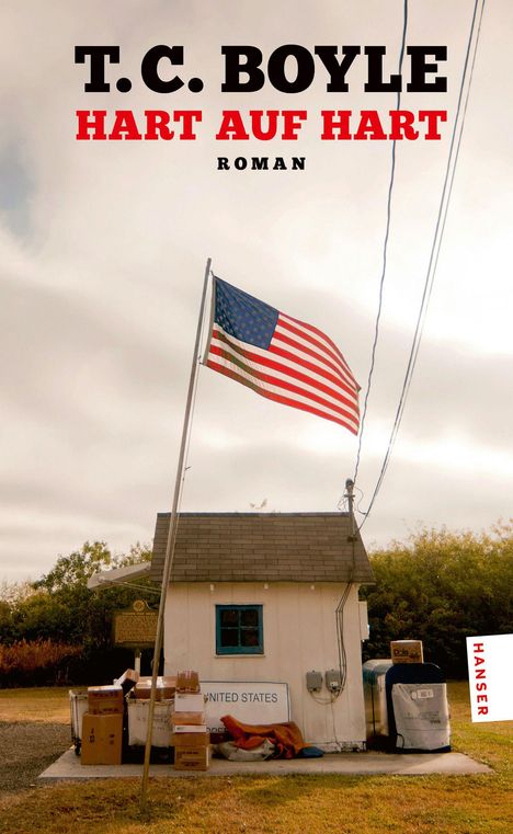 T.C. BOYLE: HART AUF HART. Unter einer US-Flagge steht ein kleines Haus mit Paketen und einem Briefkasten.