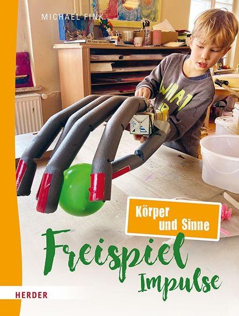 Texte: "Körper und Sinne", "Freispiel Impulse", "Michael Fink." Ein Kind baut mit großen Handattrappen am Tisch.