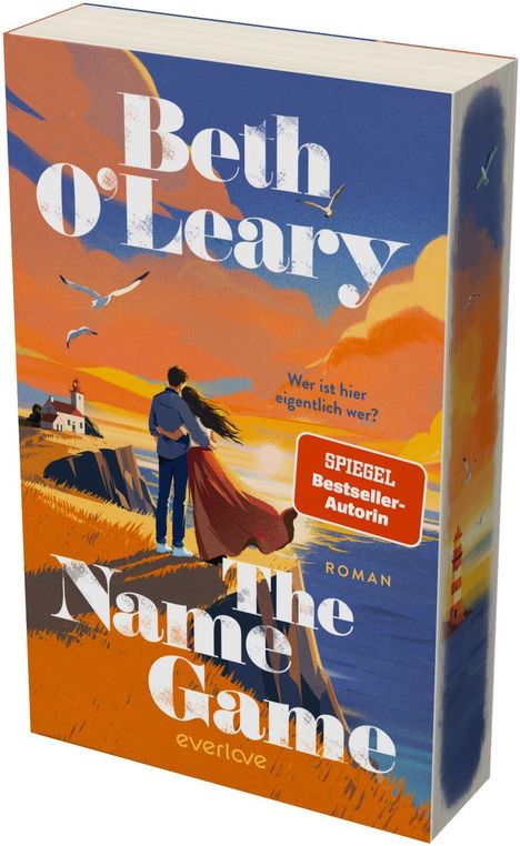 "Bestseller-Autorin", "Wer ist hier eigentlich wer?", "The Name Game", "Roman". Paar vor Küste und Leuchtturm.