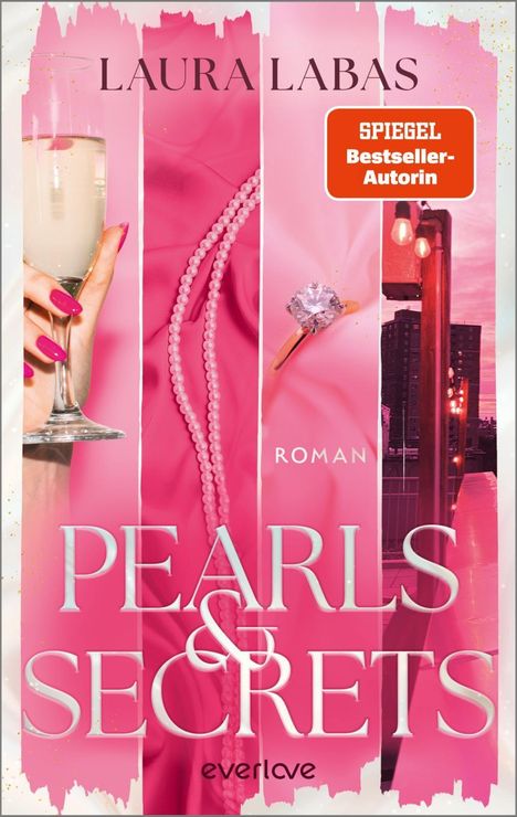 "Pearls & Secrets" von Laura Labas, Roman, SPIEGEL Bestseller-Autorin. Rosa Design mit Sektglas, Perlenkette und Ring.