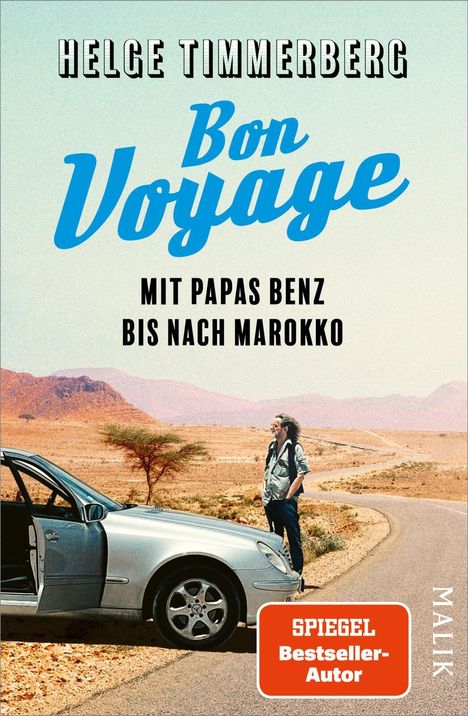 „Bon Voyage. Mit Papas Benz bis nach Marokko.“ Ein Mann steht in der Wüste neben einem offenen Auto.
