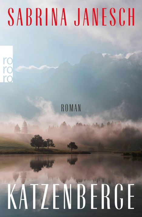 Text: "Sabrina Janesch", "Roman", "Katzenberge". Darunter eine Landschaft mit Berg, Wald und See im Nebel. Logo links oben.