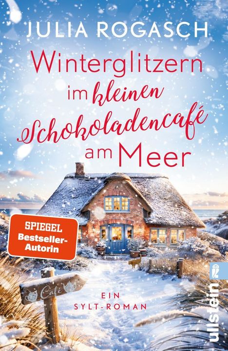 "Winterglitzern im kleinen Schokoladencafé am Meer" steht über einem verschneiten Haus mit blauem Dach und warmem Licht.