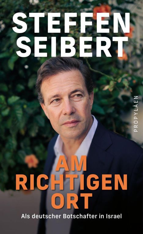 "STEFFEN SEIBERT. AM RICHTIGEN ORT. Als deutscher Botschafter in Israel." Ein Mann vor blühendem Hintergrund.