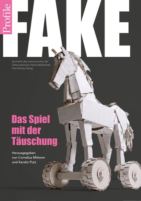 "FAKE" in großen, weißen Buchstaben. Darunter: "Das Spiel mit der Täuschung". Papp-Trojanisches Pferd auf Rädern.